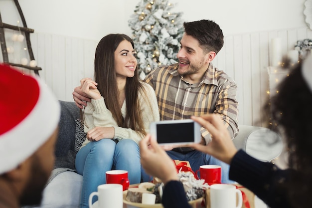 photo de Noël. Couple amoureux photographiant sur smartphone, espace copie