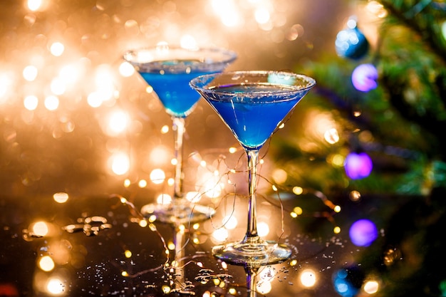 Photo de Noël de deux verres à vin avec cocktail bleu et guirlande sur le nouvel an bleu flou