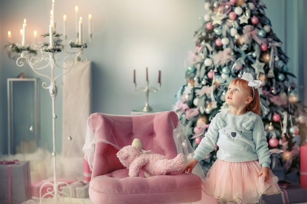 Photo de Noël d'une fillette de 3 ans près d'un magnifique sapin de Noël.