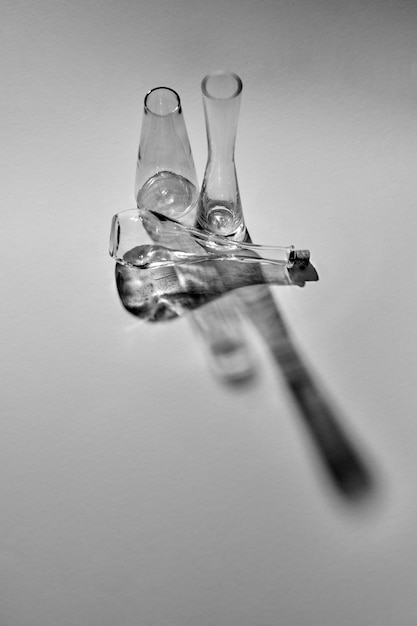 Photo en noir et blanc de bouteilles en verre sur fond gris avec des ombres