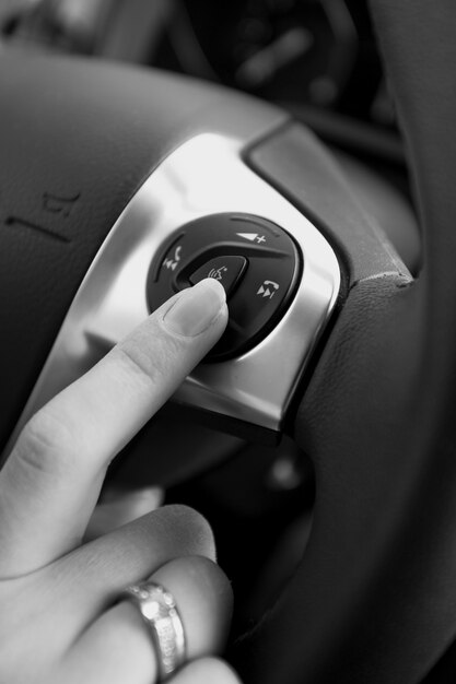 Photo en noir et blanc d'une conductrice appuyant sur le bouton du volant