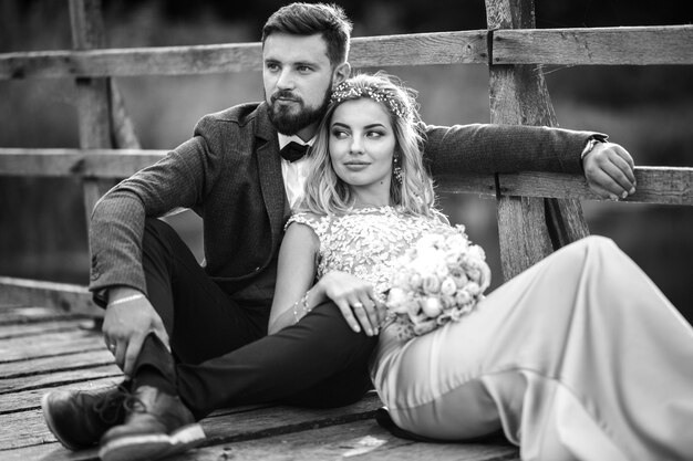 Photo noir et blanc élégant couple de jeunes mariés posant sur un pont le jour du mariage.