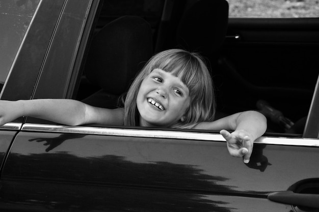 Photo en noir et blanc d'un enfant dans la voiture