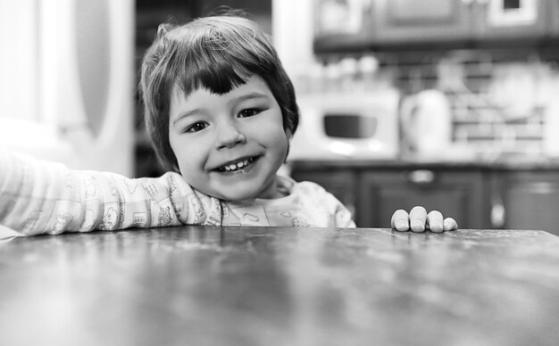 Photo en noir et blanc d'un enfant souriant et s'amusant sur fond blanc