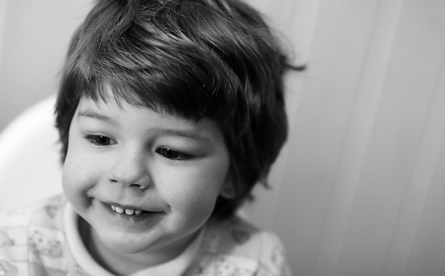 Photo en noir et blanc d'un enfant souriant et s'amusant sur fond blanc