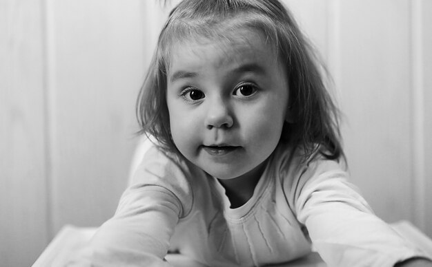 Photo en noir et blanc d'un enfant souriant et s'amusant sur fond blanc