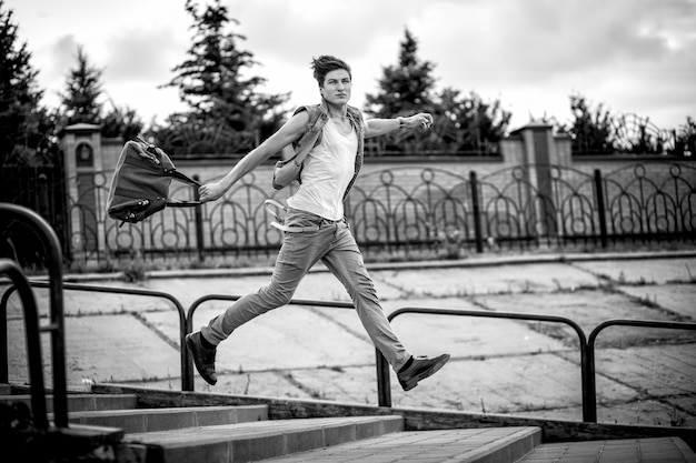 Photo en noir et blanc d'un gars avec un sac de mode qui monte les escaliers