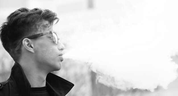 Photo noir et blanc d'un jeune homme asiatique se présentant à l'extérieur à la caméra