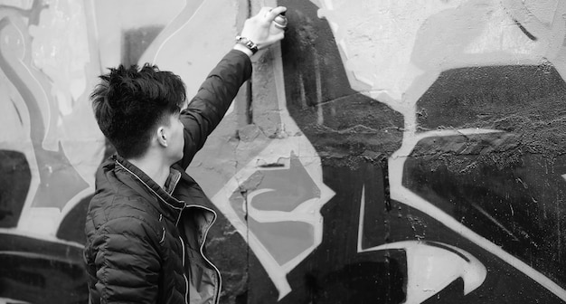 Photo noir et blanc d'un jeune homme asiatique se présentant à l'extérieur à la caméra