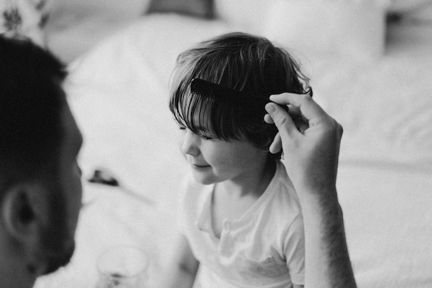 Photo En Noir Et Blanc. Le Père Coupe Les Cheveux De Son Fils Dans La Chambre