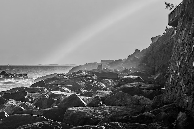 Une photo en noir et blanc de rochers et de l'océan en arrière-plan.