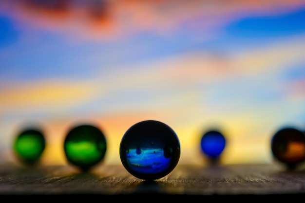 Photo de nombreuses boules de verre de couleur sur une planche de bois sur un fond flou