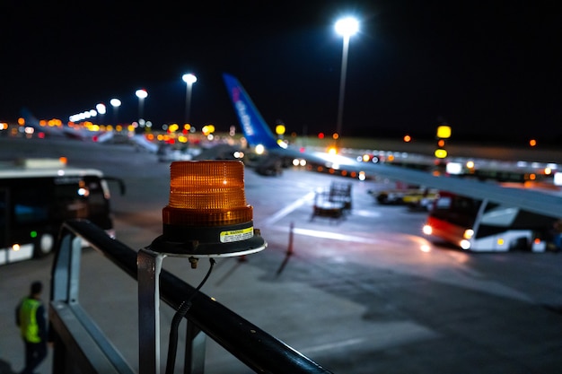 Photo de nuit, gros plan, balise jaune pour attirer l'attention sur l'équipement aéroportuaire de grande taille. Parking avion flou