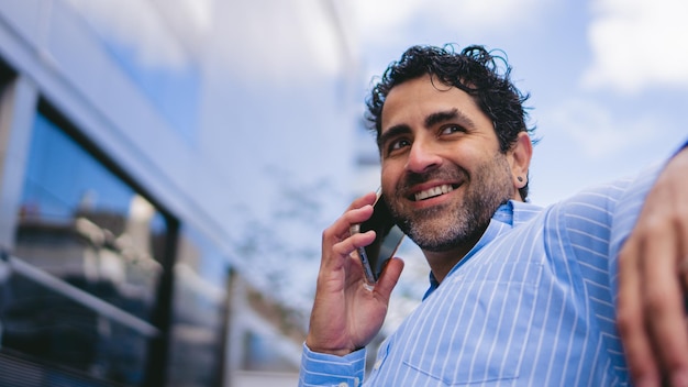 Photo panoramique d'un homme latin d'âge moyen souriant tout en parlant au téléphone Espace de copie