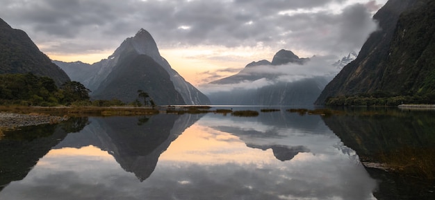 Photo de paysage panoramique du lever du soleil dans le fjord avec des pics entourés de cloudsmilford soundnew zealand