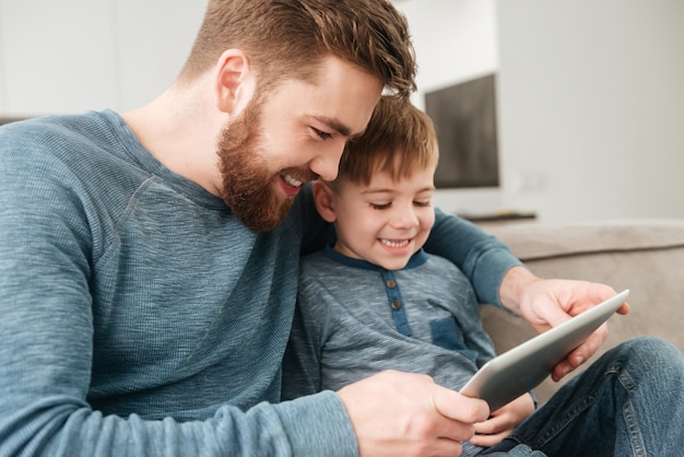 Photo d'un père heureux utilisant une tablette avec son petit fils mignon.