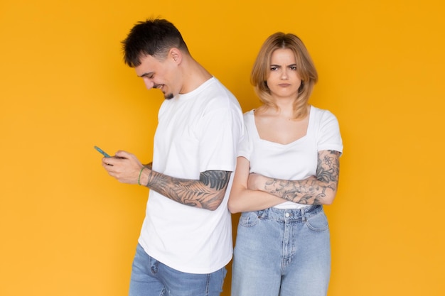 Photo de personnes excitées positives homme et femme utilisant des téléphones portables isolés sur jaune