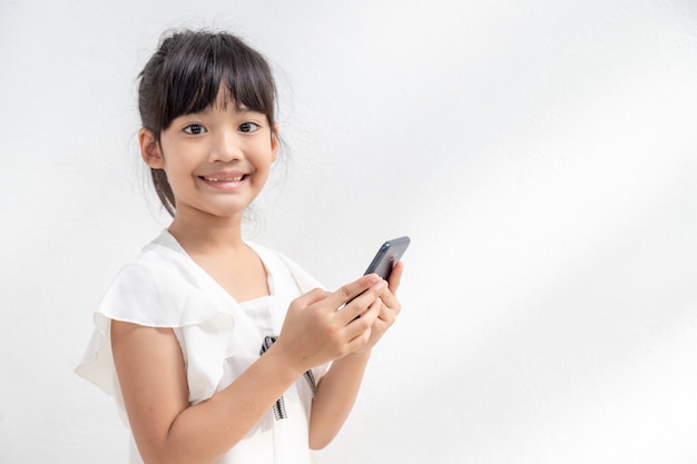 Photo d'une petite fille à l'aide d'un téléphone mobile isolé sur fond blanc