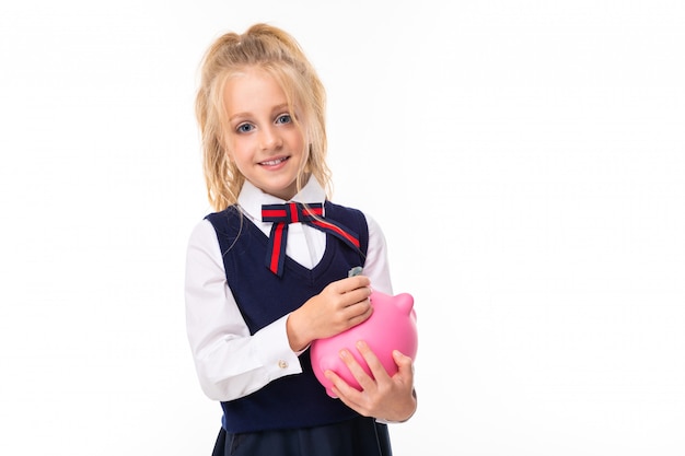 Photo d'une petite fille aux cheveux blonds détient tirelire cochon rose et sourires