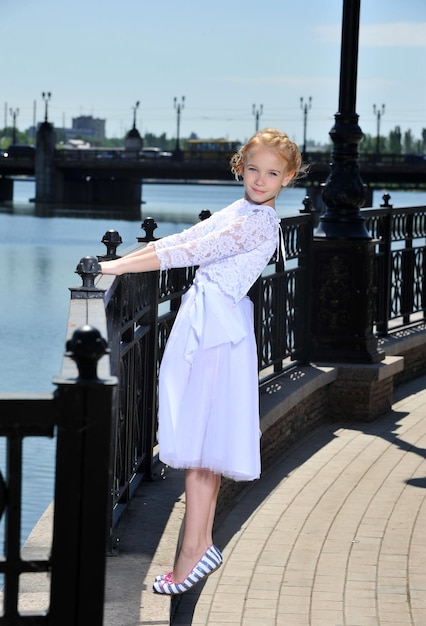 Photo d'une petite fille en robe blanche posant en plein air