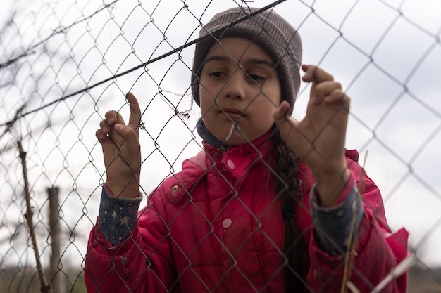 Photo d'une petite fille tenant des barreaux. Triste petite fille derrière des barreaux de fer. Petite fille derrière les barreaux. Notion de violence.