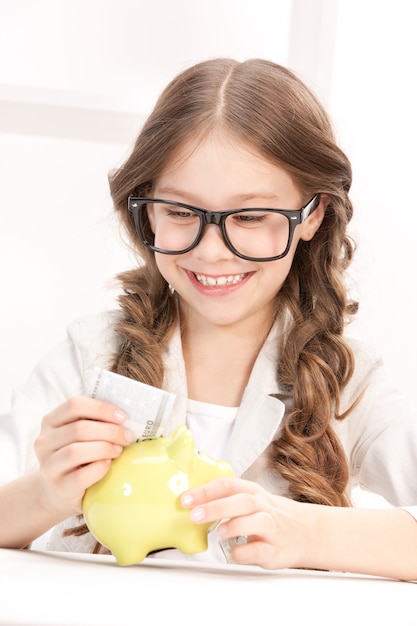 photo de petite fille avec tirelire et argent