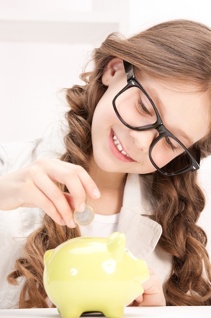 photo de petite fille avec tirelire et pièce de monnaie