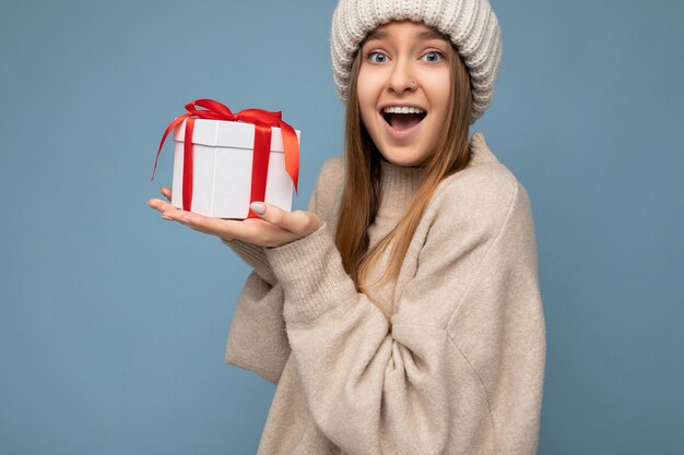 Photo photo de jolie jeune femme blonde foncée surprise heureuse isolée sur fond bleu mur