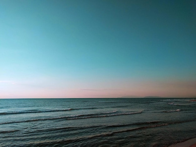 une photo d'une plage avec l'océan et le ciel en arrière-plan.