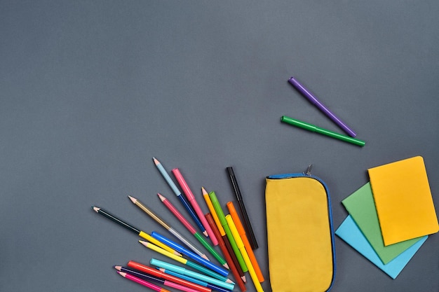 Photo à plat d'un bureau d'espace de travail avec des papeteries scolaires telles que des stylos-feutres, des autocollants pour étuis à crayons jaunes et des crayons de couleur Maquette du processus d'apprentissage Vue de dessus avec espace de copie sur fond gris