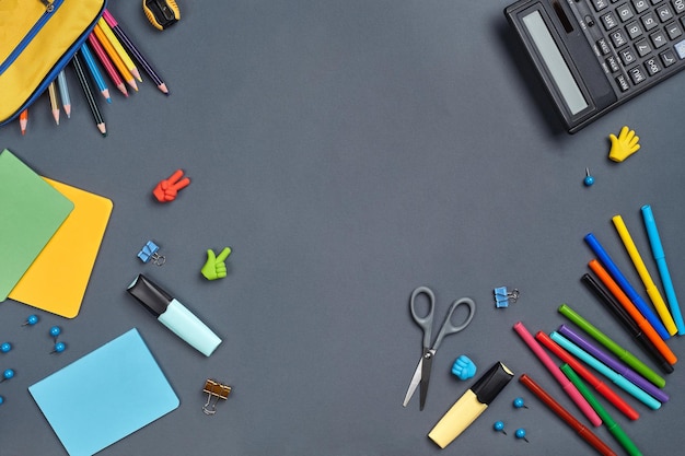 Photo à plat du bureau de l'espace de travail avec des accessoires scolaires ou des fournitures de bureau sur fond gris