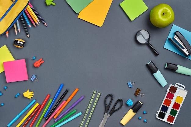 Photo à plat du bureau de l'espace de travail avec des accessoires scolaires ou des fournitures de bureau sur fond gris