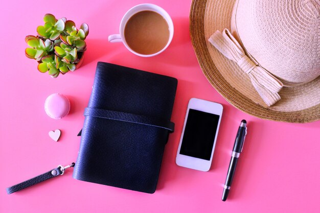 photo plat laï avec cahier, smartphone, tasse à café et plante tropicale sur fond rose