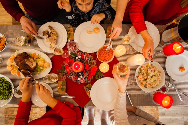 Photo à plat de la table pour la fête traditionnelle de Noël et du Nouvel An. Amis ou famille se régalant de dinde ou de poulet, légumes, vin, vue de dessus