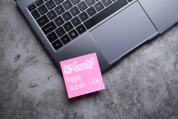 Une photo plate d'un ordinateur portable avec un postit rose pour la journée internationale de la femme le 8 mars L'avenir est féminin