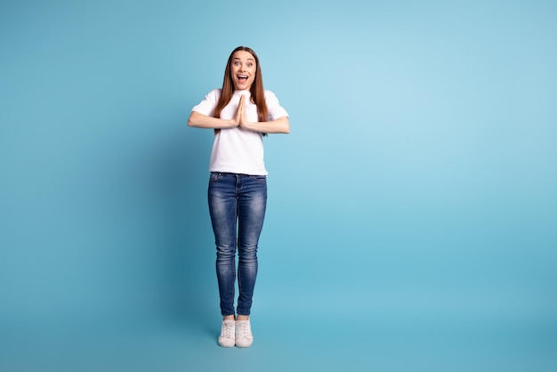 Photo pleine grandeur d'une jeune femme gaie bras ensemble plaidant cadeau rêveur isolé sur fond de couleur bleue