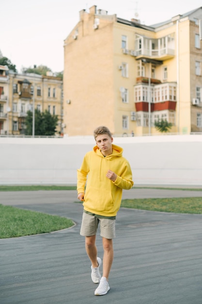 Photo pleine longueur d'un beau jeune homme dans des vêtements d'été élégants portant un sweat à capuche jaune