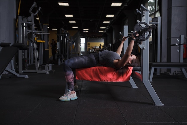 Photo pleine longueur d'une femme de fitness faisant du développé couché au studio de sport