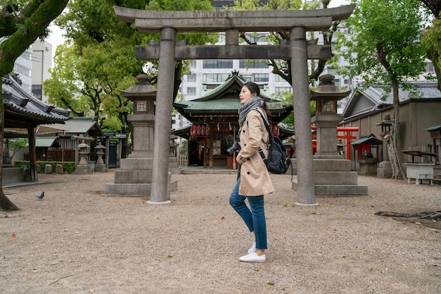 photo pleine longueur d'une femme photographe élégante mettant ses mains dans la poche, debout devant le temple