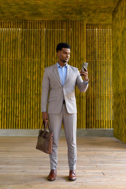 Photo pleine longueur d'un homme d'affaires africain à l'extérieur à l'aide d'un téléphone portable