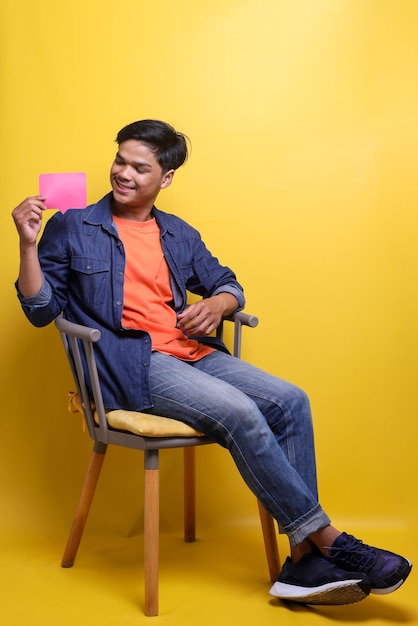 Photo pleine longueur d'un homme optimiste portant des vêtements décontractés, tenant son smartphone et commentant la forme pour les réseaux sociaux