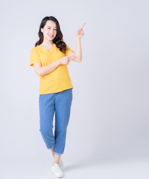 Photo pleine longueur de jeune femme asiatique debout sur fond blanc