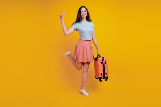 Photo pleine longueur de jeune femme séduisante heureux sourire positif sac valise voyage voler à l'étranger look isolé sur fond de couleur jaune