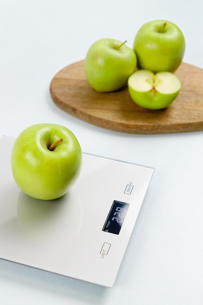 Photo de pomme verte sur une balance de cuisine Sur fond plusieurs pommes sur planche de bois Une saine alimentation