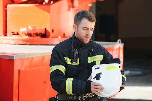 Photo d'un pompier avec masque à gaz et casque près d'un camion de pompiers