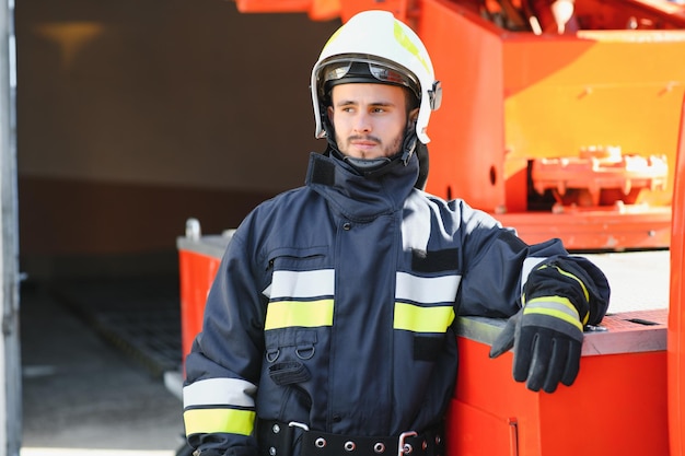 Photo d'un pompier avec masque à gaz et casque près d'un camion de pompiers