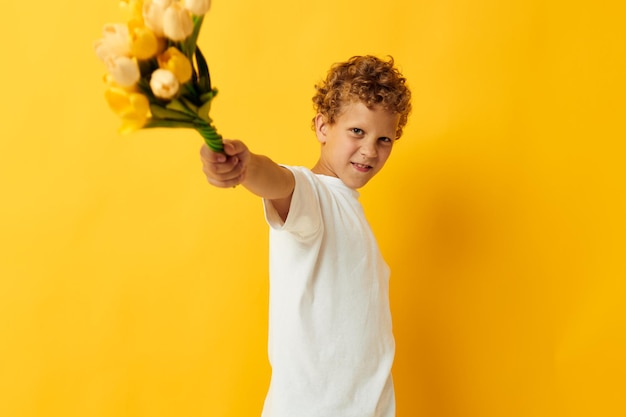 Photo portrait bouclé petit garçon avec un bouquet de fleurs jaunes fond isolé inchangé