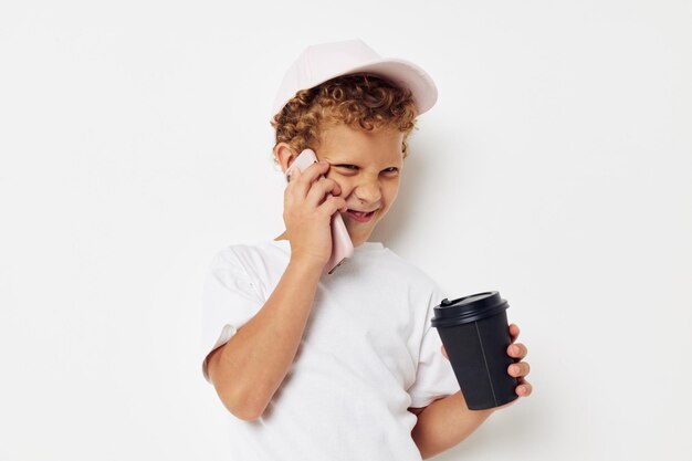 Photo portrait bouclé petit garçon quel genre de boisson est le téléphone dans la main communication fond isolé inchangé
