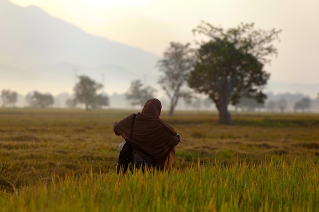 Photo de portrait d'une femme marchant parmi les rizières rurales au lever du soleil