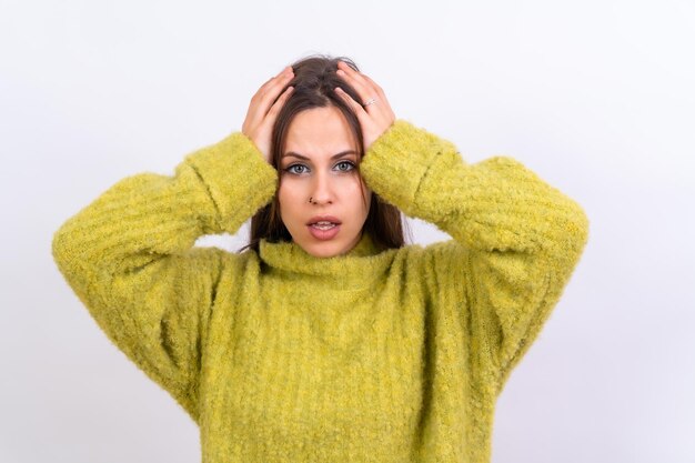 Photo portrait d'une jeune femme effrayée isolée sur un pull en laine vert fond blanc